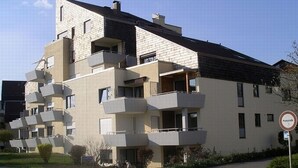 Ein mehrstöckiges Wohnhaus mit Balkonen, einem Verbotsschild und blauem Himmel.
