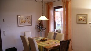 Ein Essbereich mit Tisch, Stühlen, einer Lampe und zwei gerahmten Bildern an den Wänden.