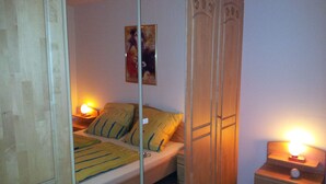 Ein Schlafzimmer mit Bett, Kleiderschrank, Nachttisch und einem Bild an der Wand.