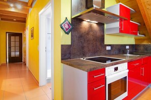 A kitchen with red cabinets, a built-in oven, and a backsplash.