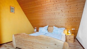 A bedroom with a wooden bed, a nightstand with a lamp, and a yellow wall. - Saupp Apartment with Garden and Wi-Fi (Immenstaad am Bodensee)