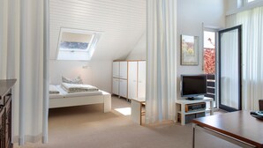 Een slaapkamer met een bed, een televisie, een bureau, een kledingkast en een raam.