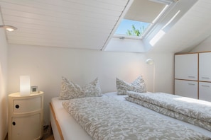 Une chambre avec un puits de lumière, une table de chevet avec une lampe et une armoire.