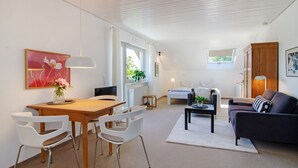 A modern interior with a dining area, a sofa, and a window. - Apartment Riedel '1-Room Apartment, 45 sqm' with Shared Garden, Balcony and Wi-Fi (Immenstaad am Bodensee)