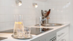 A kitchen with a water pitcher, a glass, and a sink. - Apartment Riedel '1-Room Apartment, 45 sqm' with Shared Garden, Balcony and Wi-Fi (Immenstaad am Bodensee)