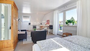 A modern room with a bed, a desk, a chair, a wardrobe, and a window with a view. - Apartment Riedel '1-Room Apartment, 45 sqm' with Shared Garden, Balcony and Wi-Fi (Immenstaad am Bodensee)