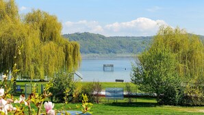 Eine friedliche Uferlandschaft mit Weidenbäumen, einer Bank und einer Wasserradstation.