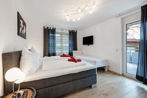 A bedroom with a bed, bedside tables, a TV, and a sliding glass door.