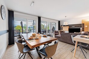 Een moderne woonkamer met een eetgedeelte, grote ramen en uitzicht op de omgeving.