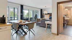 Eine moderne Küche mit Essbereich, großen Fenstern und Blick ins Grüne.