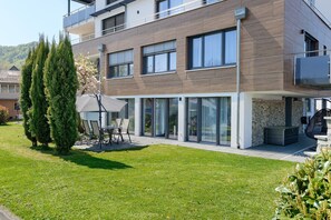 Um edifício residencial moderno de dois andares com telhado plano, janelas grandes e uma varanda.