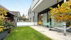 Et moderne hus med en velplejet græsplæne, udendørs møbler og en stenvæg.