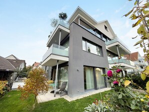 A modern two-story residential building with a balcony, large windows, and a well-maintained garden. - Apartment 'Ins Blaue, 73qm' with Balcony and Wi-Fi (Langenargen)