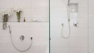Ein Badezimmer mit Dusche, Badewanne und Glasabtrennung.