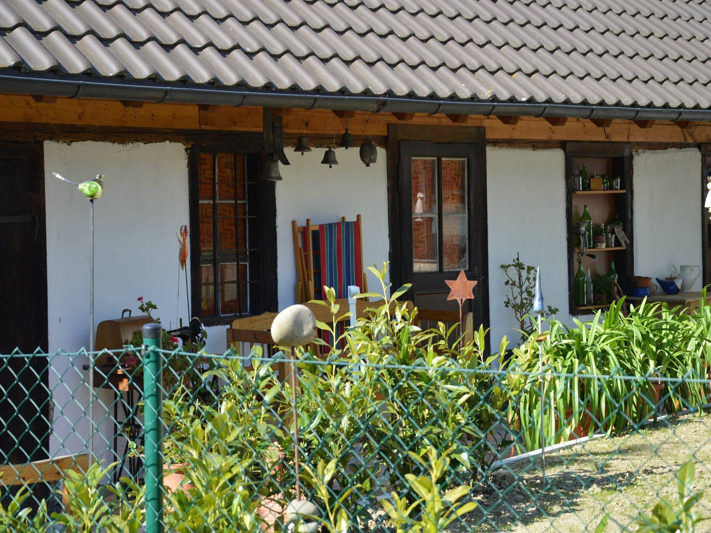 Ein traditionelles Haus mit einem Ziegeldach, einer hölzernen Veranda und einem umzäunten Garten.