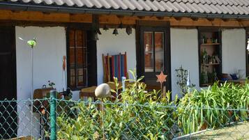 Ein traditionelles Haus mit einem Ziegeldach, einer hölzernen Veranda und einem umzäunten Garten.