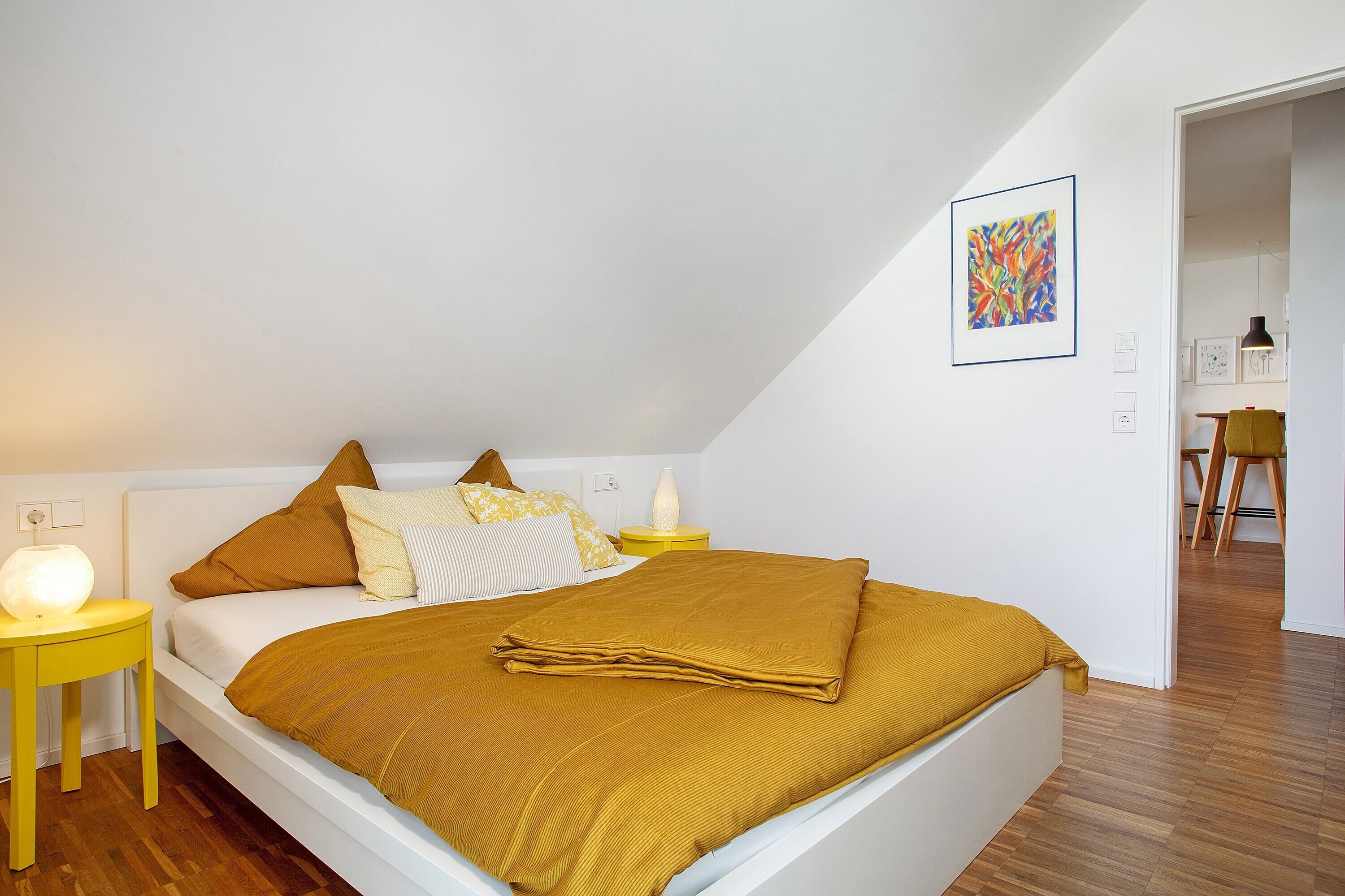 Ein Schlafzimmer mit Bett, Nachttischen, einer Lampe und einem Gemälde an der Wand.