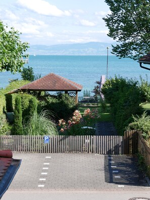 Un gazebo con tetto in tegole, un ingresso pavimentato e vista su un corso d'acqua con montagne sullo sfondo.