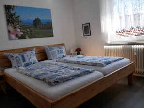 A double bed with a wooden frame and blue patterned bedding. - Haus Alpenblick – Happiness Apartment with Balcony and Wi-Fi (Immenstaad am Bodensee)