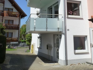 A two-story building with a balcony, a door with a number plate, and a window with flowers. - Haus Alpenblick – Happiness Apartment with Balcony and Wi-Fi (Immenstaad am Bodensee)