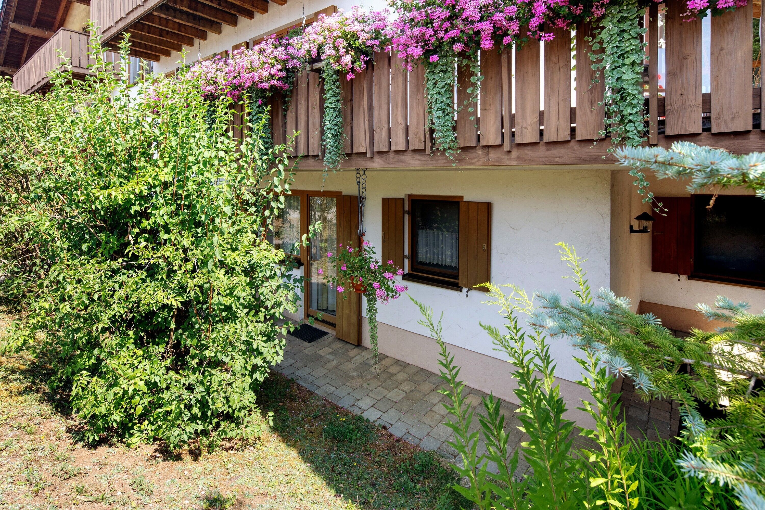 A two-story building with a wooden balcony and a small garden area.