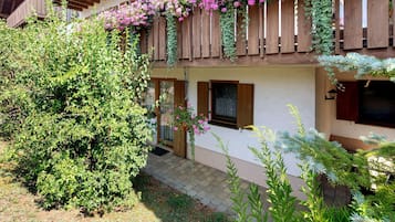 A two-story building with a wooden balcony and a small garden area.