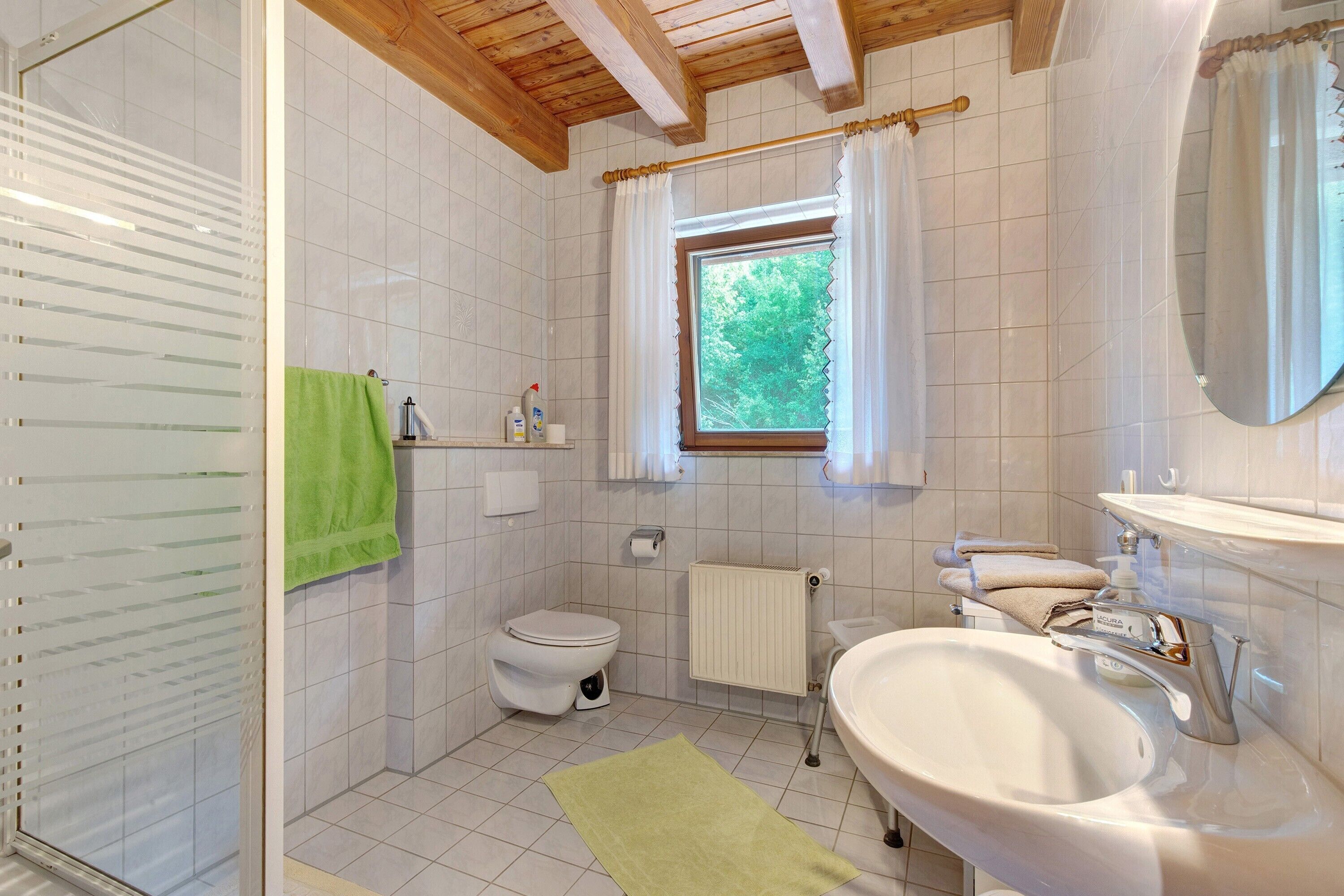 Ein Badezimmer mit Toilette, Waschbecken, einem Fenster mit Vorhängen und einem Handtuchhalter.