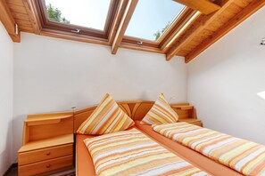 A bedroom with a skylight, wooden bed frame, and a single bed with striped bedding. - Apartment 'C' with Balcony and Wi-Fi (Lonsee)
