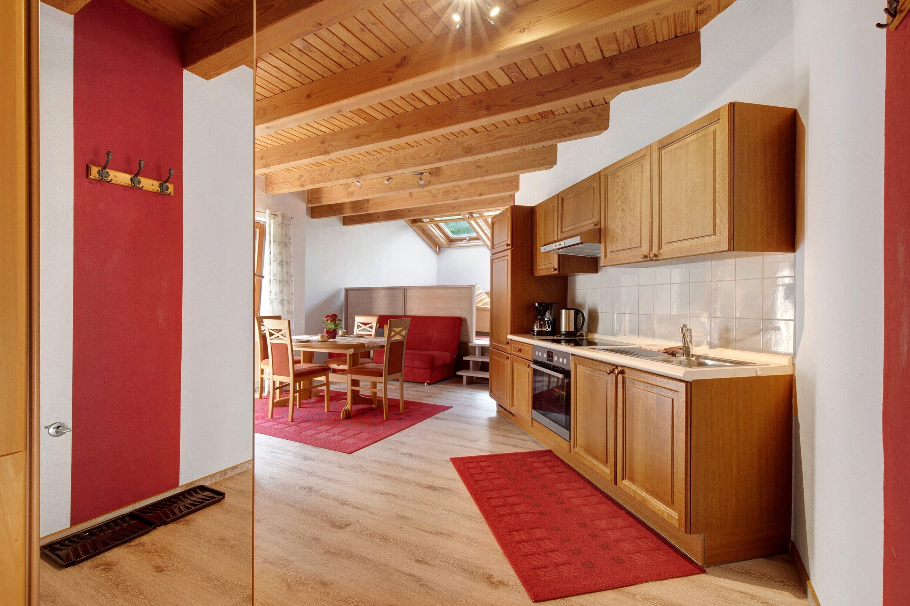 Eine moderne Küche mit Holzschränken, einem roten Teppich und einem Essbereich mit Tisch und Stühlen.