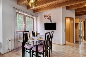 A dining area with a glass table, chairs, and a vase with a flower.
