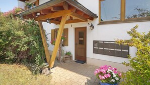 A house with a wooden pergola, a mailbox, and a door with a number. - Apartment 'H' with Balcony and Wi-Fi (Lonsee)