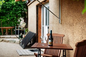 Een houten tafel met een fles en twee glazen, een stoel, en een deur op de achtergrond.