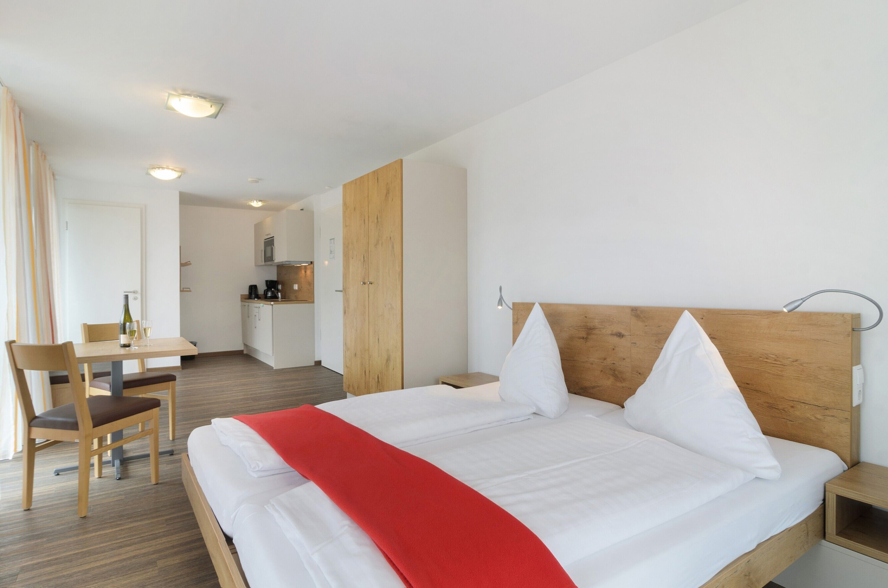 Ett hotellrum med en säng, ett skrivbord och ett litet kök.