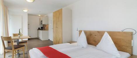 Ett hotellrum med en säng, ett skrivbord och ett litet kök.