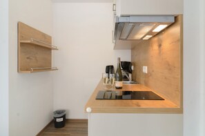 A compact kitchen with a wooden countertop, a wine bottle, glasses, and a trash bin labeled 'Papier'. - Apartment Type A with 28 sqm for 1-2 Persons (Immenstaad am Bodensee)