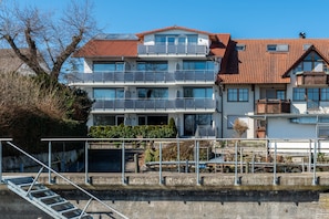 Een meerlaags gebouw met balkons, een trap en uitzicht op het water.