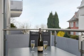 Een fles wijn en twee glaasjes op een balkontafel.