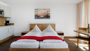 Et moderne hotelværelse med seng, et billede, et spisebord og et tekøkken.
