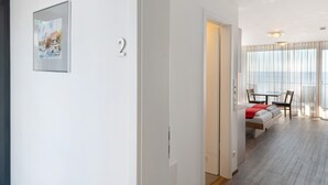 Et moderne hotelværelse med seng, siddeplads, spisebord og et stort vindue med gardiner.