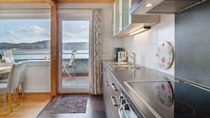 A modern kitchen with a large window, a dining area with a view, and a kitchen island. - Apartment '8, 53 sqm, Directly on Lake Constance with Lake Access (Bodman-Ludwigshafen)