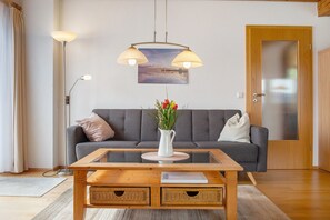 Un salon moderne avec un canapé, une table basse, un lampadaire et un tableau accroché au mur.