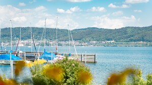 A marina with boats docked, a wooden pier, and a hilly landscape in the background.