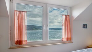 Ein Zimmer mit großem Fenster, einem Bett und einem kleinen Tisch.