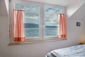 Una habitación con un ventanal grande, una cama y una mesita.