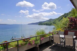 Une terrasse au bord du lac, avec des sièges en plein air et une vue sur le lac et les collines.