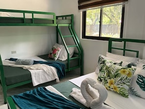 A room with bunk beds, a window with a view, and a bed with a decorative pillow.