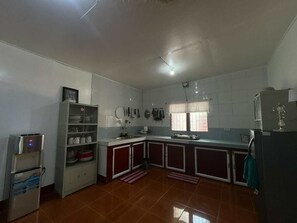 A kitchen with a refrigerator, a water dispenser, a sink, and cabinets.