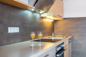 Una cocina moderna con horno integrado, un lavamanos y dos vasos de zumo de naranja sobre la encimera.