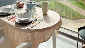 Un balcón con mesa lista para comer, con vistas a un edificio de hotel y una calle.