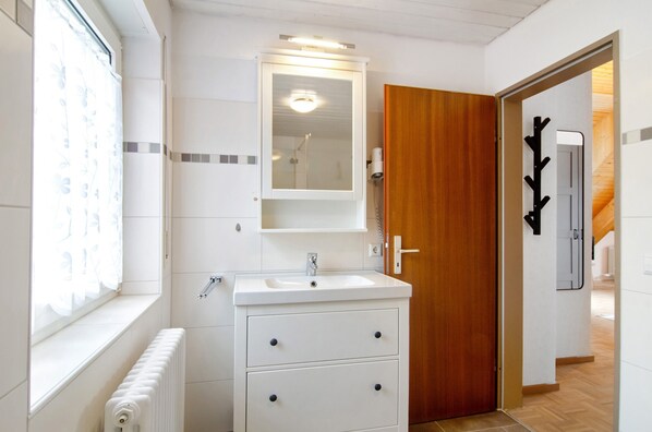 A bathroom with a white sink, mirror, and wooden door.